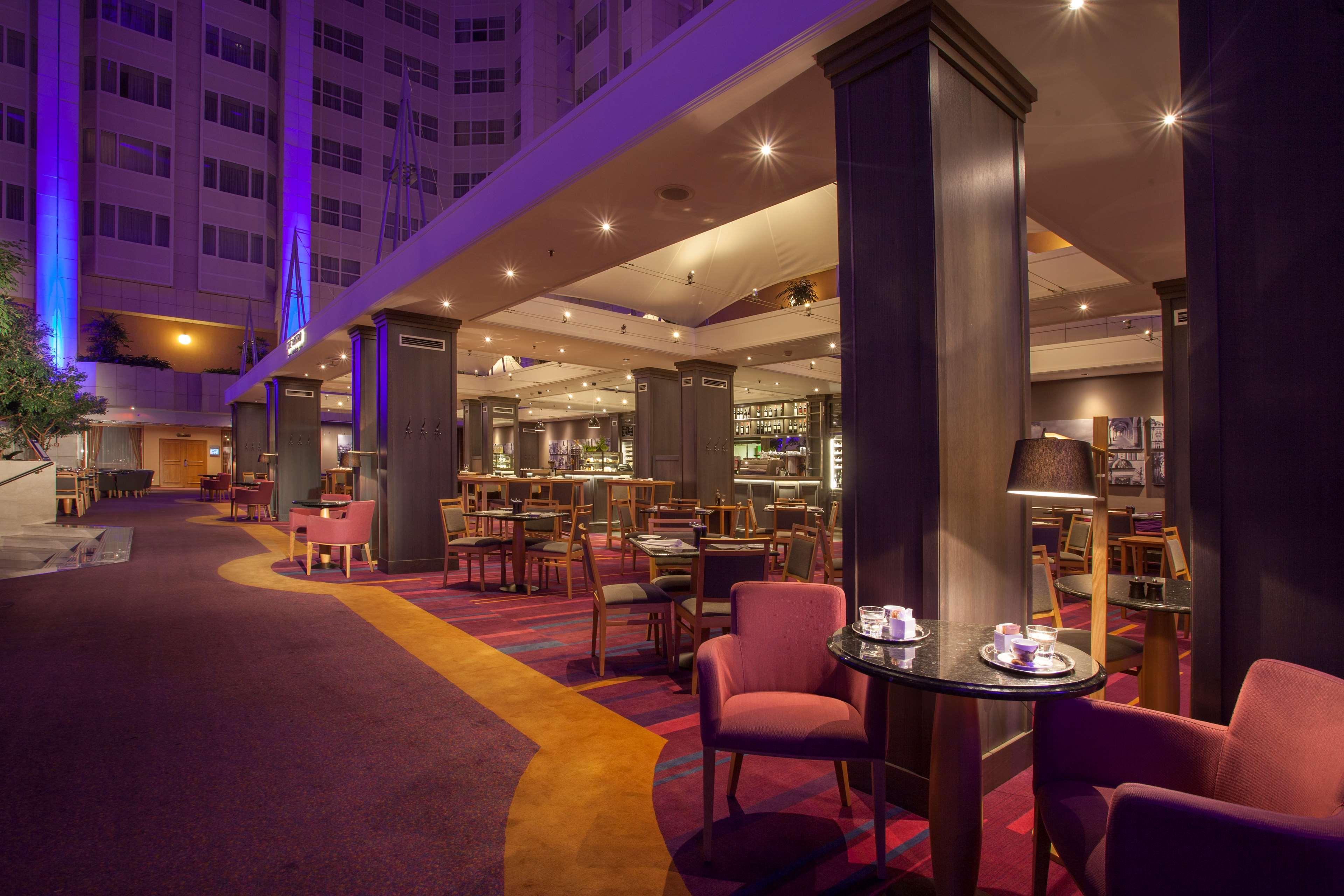 Hilton Prague Hotel Exterior foto The photo depicts a modern, stylish interior of a dining or lounge area, possibly within a hotel. 

- The space features a combination of comfortable seating arrangements, including plush pink chairs arranged around small tables.
- The lighting is wa